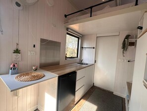 Eine kleine Küche mit Holzausziehtisch, integriertem Geschirrspüler, Fenster und Tür.