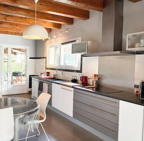 A modern kitchen with a large island, white cabinets, and a wooden ceiling. - 46G12083 - CREMPS - Gîte (CREMPS)