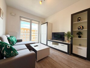 A modern living room with a sofa, coffee table, TV, and a plant. - Tarnogaj Modern Apartment (Wrocław)