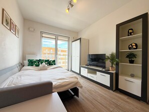 A modern hotel room with a bed, a TV, a desk, and a wardrobe. - Tarnogaj Modern Apartment (Wrocław)