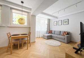 Ein modernes Wohnzimmer mit Esstisch, einer Couch und einem Flachbildfernseher.