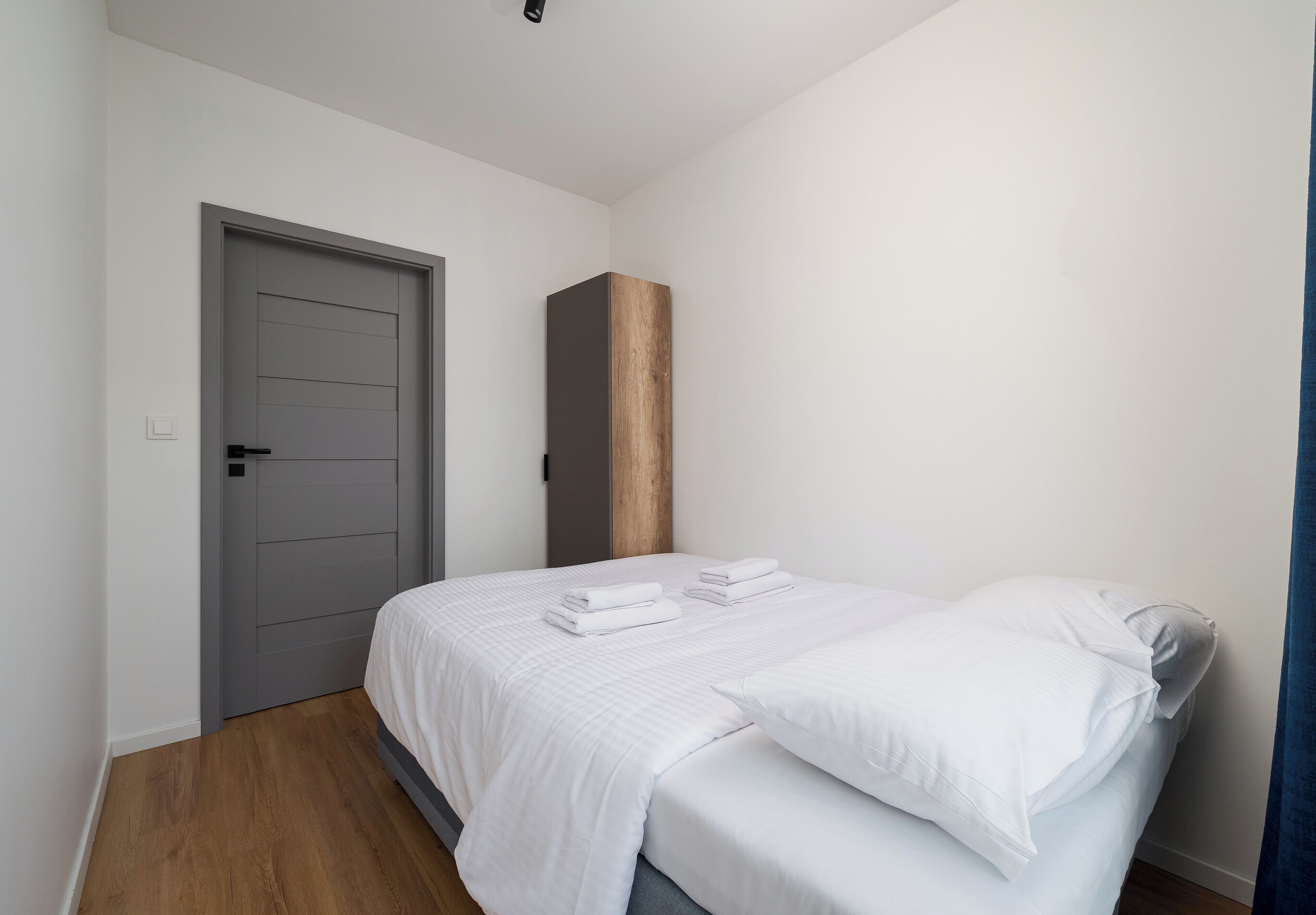 Un dormitorio con cama, una puerta y un panel de madera en la pared.