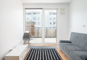 Ein modernes Wohnzimmer mit einem grauen Sofa, einem weißen Schrank und einem schwarz-weißen Teppich.