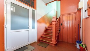 Un escalier avec une rampe rouge menant à une porte dont les panneaux sont en verre dépoli.