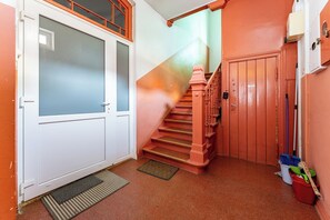Eine Treppe mit roter Handlauf, die zu einer Tür mit sandgestrahlten Glasscheiben führt.