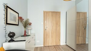 Une chambre moderne avec une porte en bois, un miroir, un globe terrestre et un bureau avec une lampe.