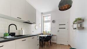 Une cuisine moderne avec des meubles blancs, un plan de travail noir et un coin repas comprenant une table et des chaises.