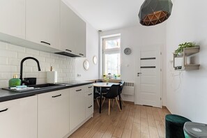 Eine moderne Küche mit weißen Schränken, einer schwarzen Arbeitsplatte und einem Essbereich mit Tisch und Stühlen.