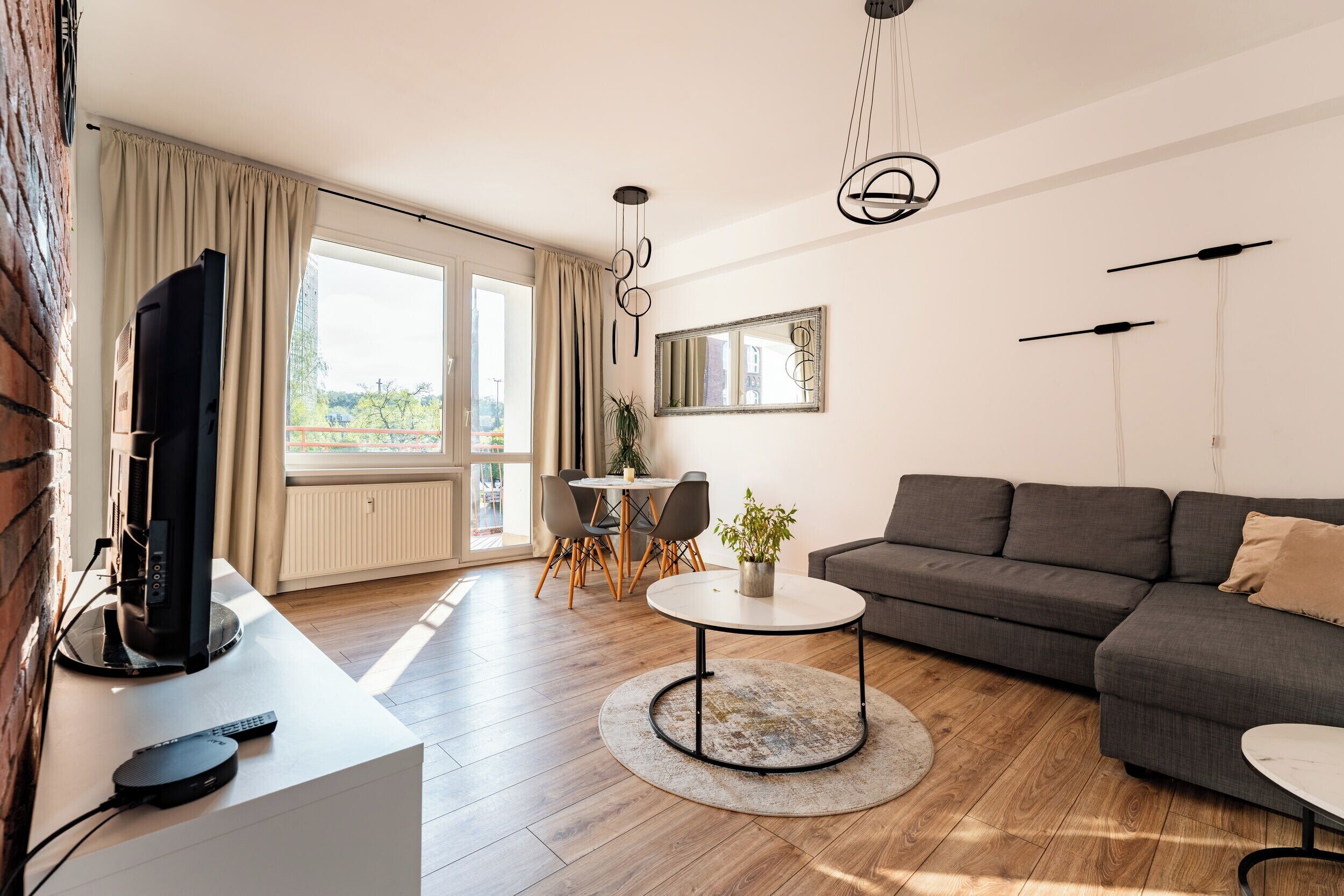 Ett modernt vardagsrum med en soffa, en tv och en matplats.