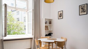 A room with a round table, four chairs, a bookshelf, and a window with curtains. - Solec Powiśle Chic Apartment (Warszawa)