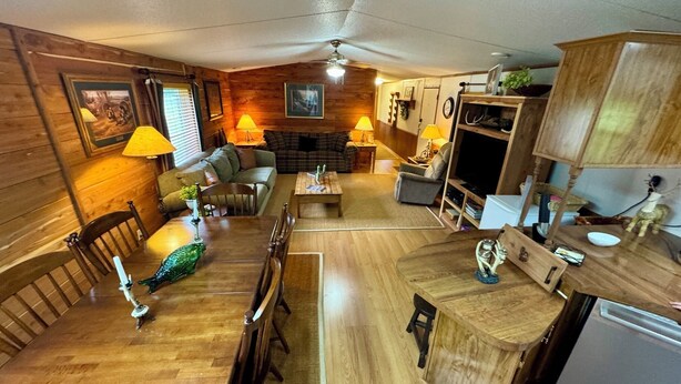 Ein gemütliches Blockhauskamin-Interieur mit einem Holzespeisesaal, Stühlen, einer Couch, einem Fernseher und einer Küchenzeile.