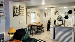 A compact living space with a dining area, kitchenette, and a green sofa. - The Cozy Cottage at the base of Pikes Peak with private hot tub (Cascade-Chipita Park)