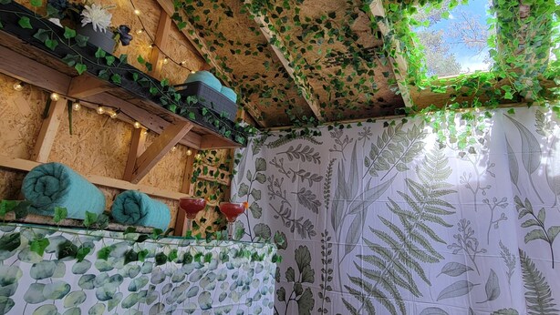 A room with a wooden ceiling, ivy, string lights, a bed, and a window with a view. - The Cozy Cottage at the base of Pikes Peak with private hot tub (Cascade-Chipita Park)
