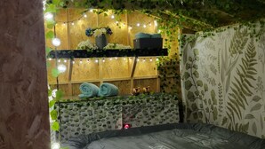 A cozy room with a stone wall, a wooden shelf with flowers, and string lights. - The Cozy Cottage at the base of Pikes Peak with private hot tub (Cascade-Chipita Park)