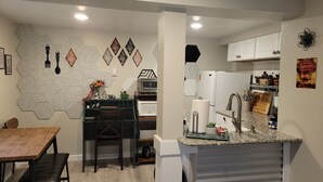 A modern kitchen with a dining area, featuring a hexagonal tile backsplash, a built-in oven, and a granite countertop. - The Cozy Cottage at the base of Pikes Peak with private hot tub (Cascade-Chipita Park)