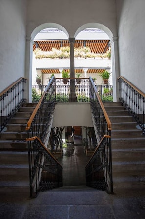 Eine imposante Treppe mit aufwendiger schwarzer Geländerkonstruktion und Holzhandläufen, die zu einer erhöhten Ebene mit Blick auf einen Garten führt.