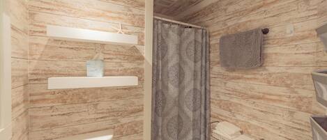 Un baño con diseño de pared de madera, un inodoro, una cortina de ducha y un perchero para toallas.