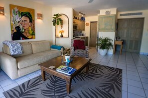 Ein Wohnzimmer mit Sofa, Sessel, Couchtisch und einem Bild an der Wand.