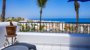 A balcony with a view of the sea, palm trees, and buildings. - Cozy Condo/Ocean view/ Private balcony/Paseo la Jolla/ San Jose del Cabo (San José del Cabo)