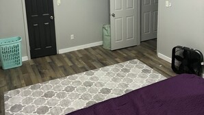 Un dormitorio con cama, ventilador de techo, cesto de ropa y dos puertas.