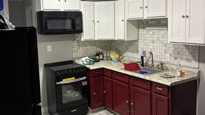 Una cocina con armarios blancos, un horno negro y un microondas.