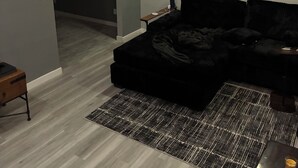 Una sala moderna con un sofá modular, una alfombra estampada e iluminación empotrada en el techo.