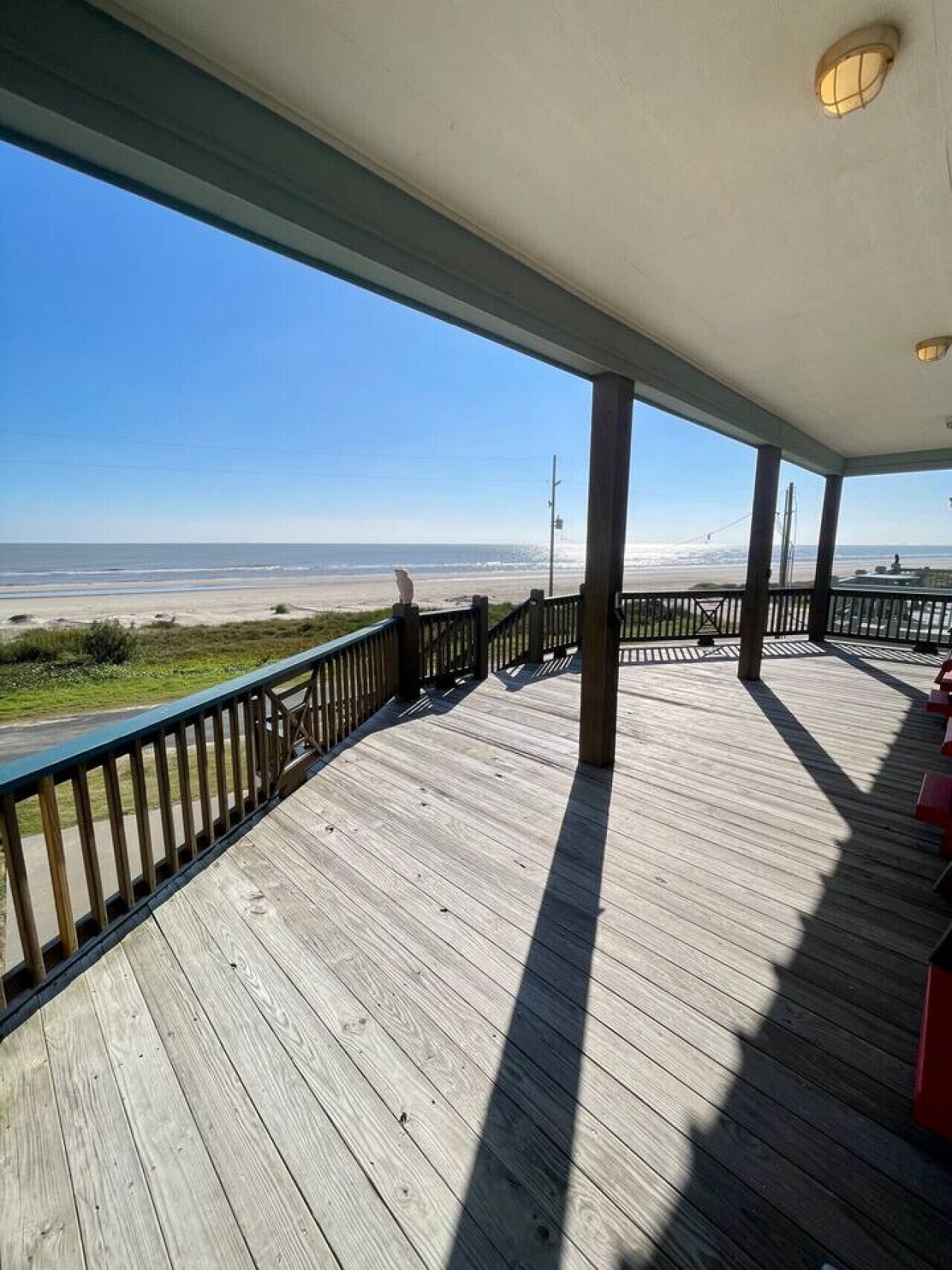 A wooden deck with a railing overlooking a beach.