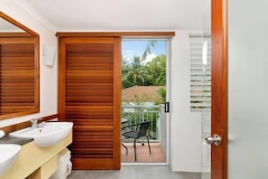 Un baño con puerta de madera, un lavabo y un espejo.