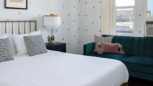 A bedroom with a bed, a green sofa, a nightstand, and a window with curtains. - Serene studio with AC in vibrant Los Angeles neighborhood (Los Angeles)