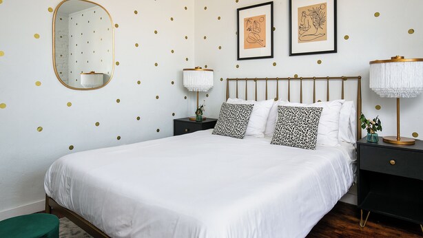 A bedroom with a bed, nightstands, a mirror, and wall art. - Serene studio with AC in vibrant Los Angeles neighborhood (Los Angeles)
