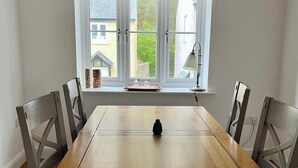 A dining table with chairs, a window with a view of buildings, and a lamp on the windowsill.