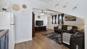 Ein modernes Wohnzimmer mit Flachbildfernseher, einer Ledersofa und einem Essbereich inklusive Kühlschrank.