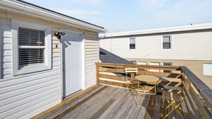 Ein Wohngebäude mit Holzterrasse, einer Tür und einem Fenster mit Jalousien.