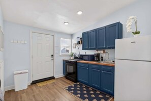 Cocina pequeña con armarios azules, un refrigerador blanco y un microondas.