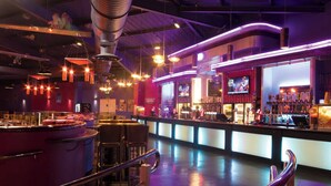 Eine Bar mit einer Theke, Hockstühlen und einem Fernsehbildschirm.