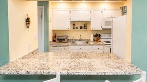 A compact kitchen with white cabinets, a granite countertop, a toaster, a sink, and a stove. - 2BR Beach Bungalow | Walk to Beach | Sleeps 5 (Norfolk)