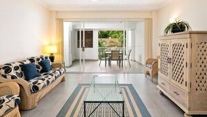 Una sala de estar con un sofá, una mesa de centro de vidrio y un mueble.