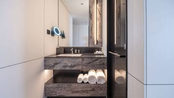 A modern bathroom with a marble sink, a large mirror, and a towel rack.