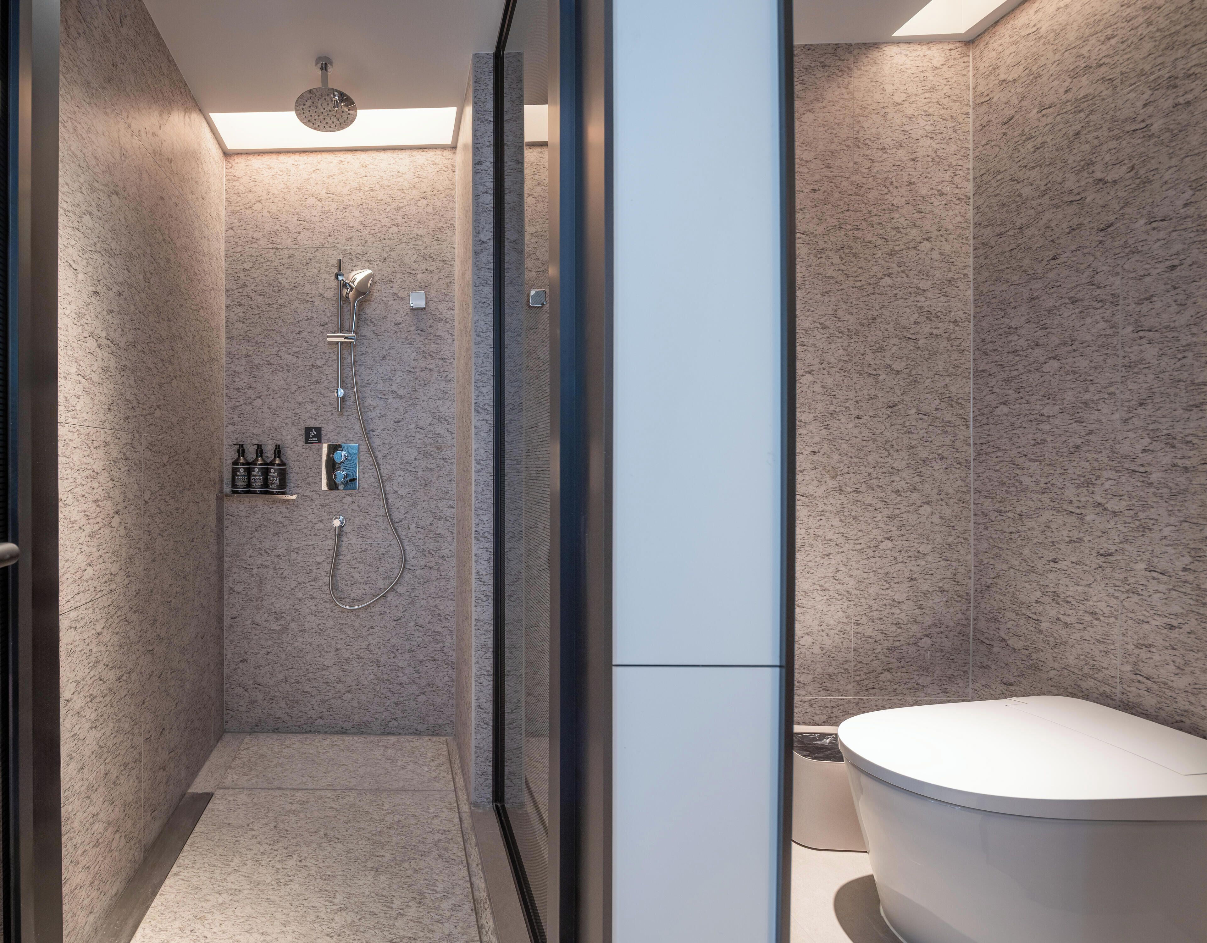 A modern bathroom with a shower, toilet, and a glass door.