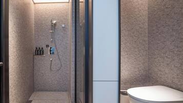 A modern bathroom with a shower, toilet, and a glass door.