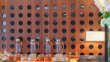 Un mostrador de recepción con un panel de pared de madera, un jarrón con flores y distintos vasos y recipientes.