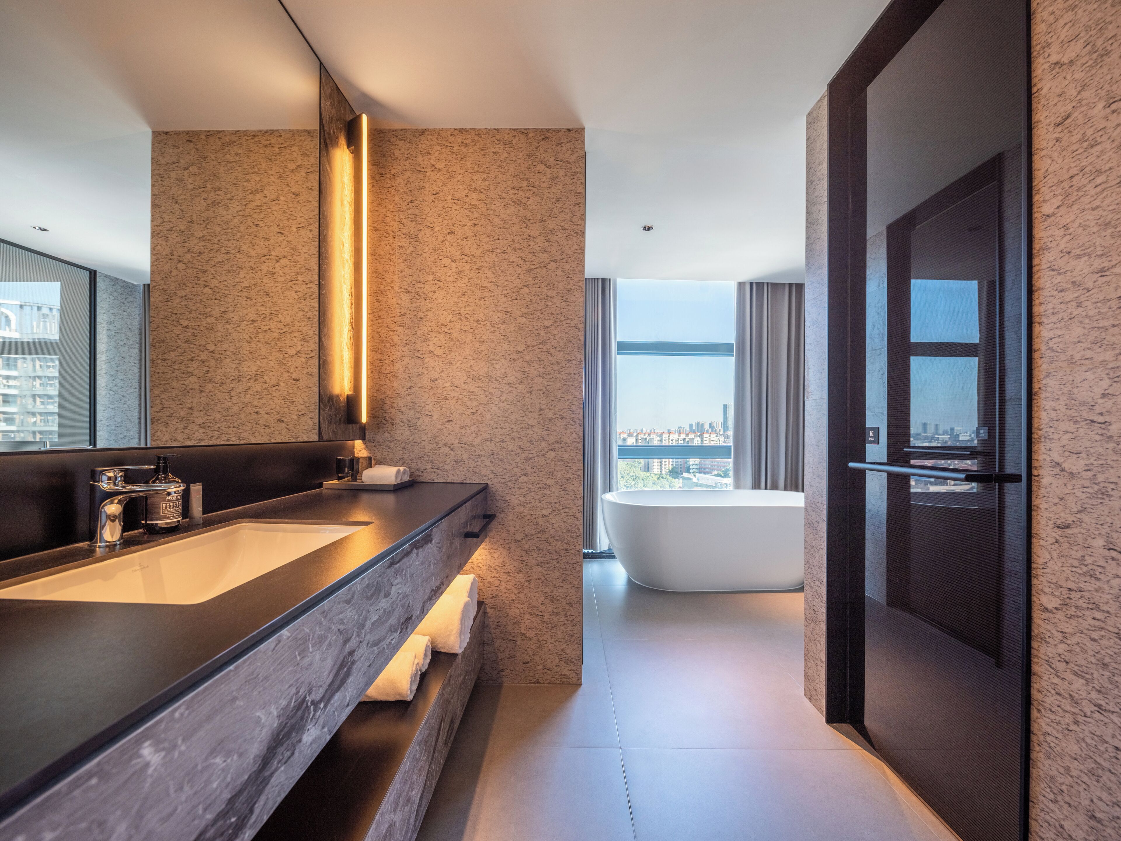 Une salle de bain moderne avec un grand lavabo, un miroir, une baignoire et une vue sur la ville.