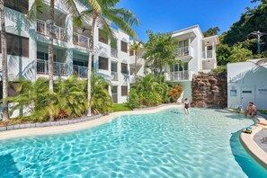 A resort with a swimming pool, multi-story buildings, and lush greenery. - Alassio 203-2 | Studio Room (Palm Cove)