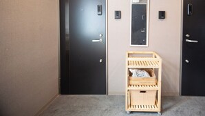A hotel room with two black doors, a small wooden cart with baskets, and a wall-mounted mirror. - 5963 Hotel Higashi Ikebukuro (Tokyo)