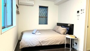A small, neatly arranged bedroom with a bed, bedside table, and a window. - 5963 Hotel Higashi Ikebukuro (Tokyo)