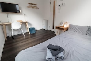 A hotel room with a bed, a desk with a chair, a television, a heater, and a bedside table with a lamp. - 5963 Hotel Higashi Ikebukuro (Tokyo)
