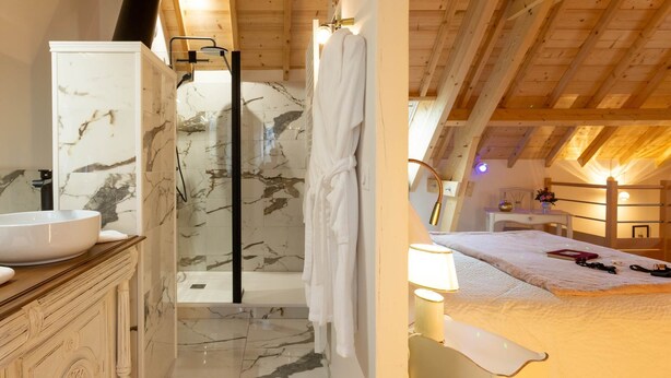 A bathroom with a marble sink, a glass shower enclosure, and a wooden ceiling.