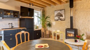 A cozy kitchen with dark cabinets, a round dining table, and a wood-burning stove.