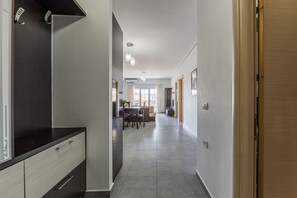A hallway with a kitchen area, dining table, and chairs. - Flower Balcony Apartment 2BR Beachside Escape (Sarandë)