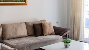 Een woonkamer met een bank, een bijzettafeltje en een potplant.
